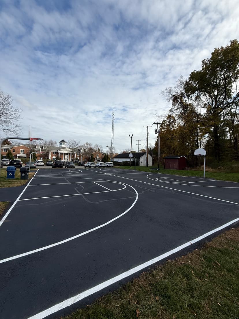 Empty basketball court with clear lines and a view of trees and buildings in the background.