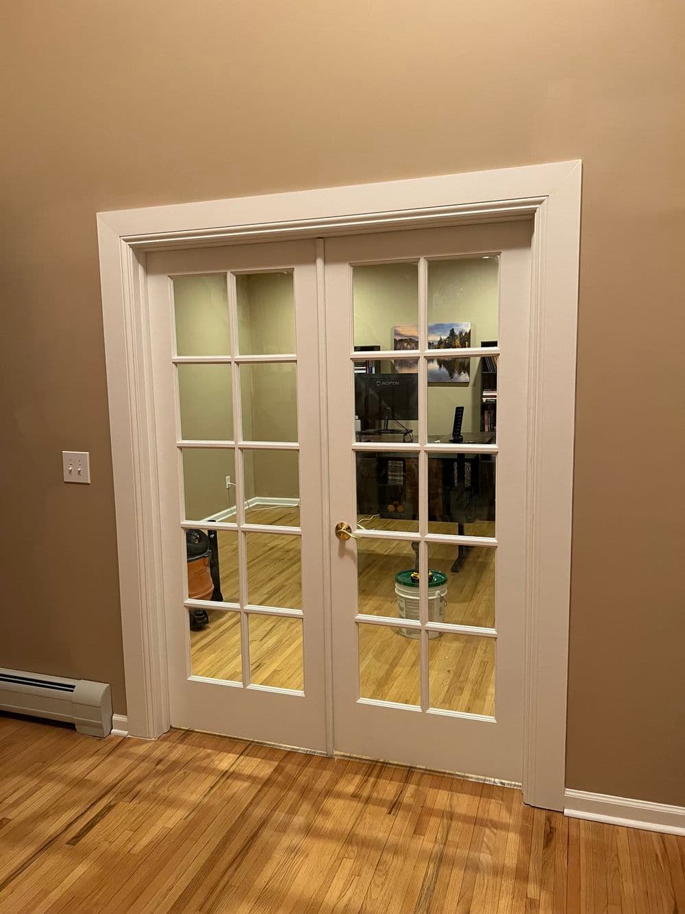 French doors with glass panes, leading to a wooden floor room with soft lighting.