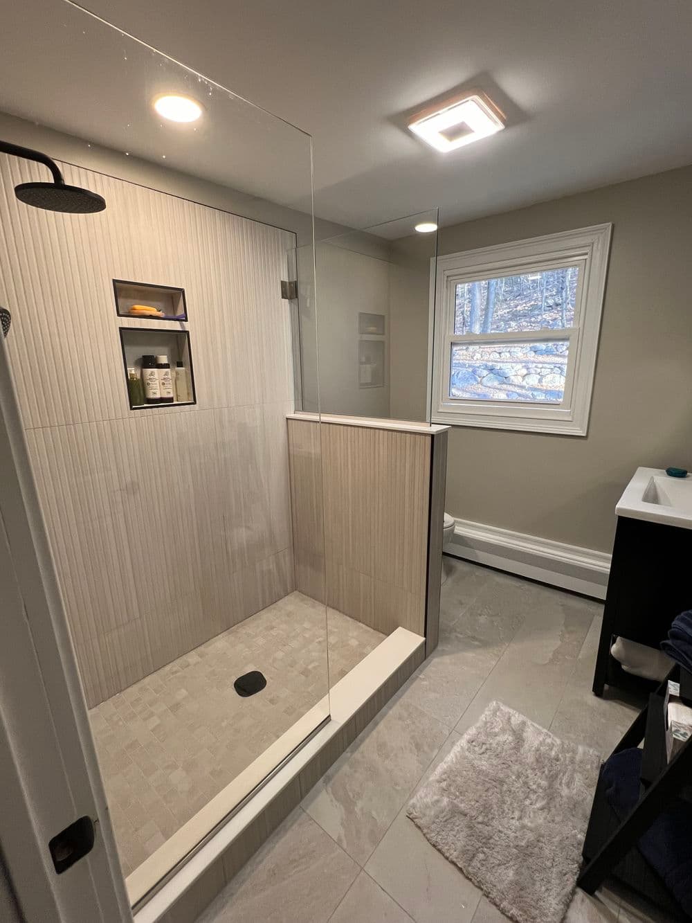 Modern bathroom featuring a walk-in shower, neutral tones, and natural light from a window.