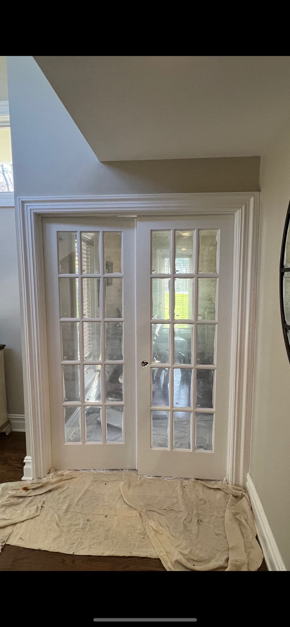 White French doors with glass panels in a bright room, framed by elegant trim.